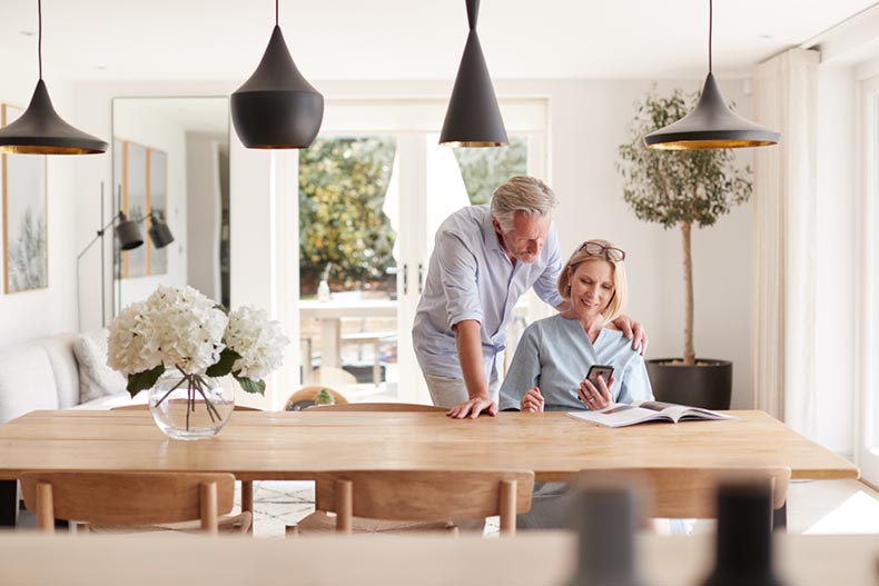 A senior couple at a table smiling while researching homes for sale in a maintenance-free 55+ community