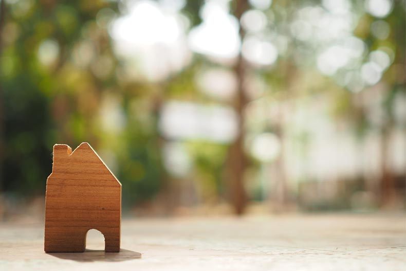 A small, wooden cutout of a house with a blurred nature background