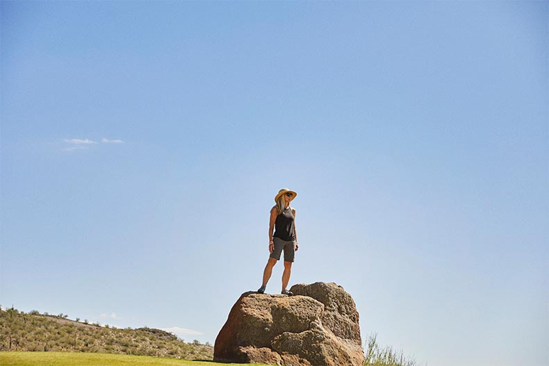An active adult woman standing on a rock and looking out over the landscape