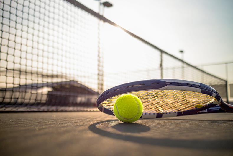 A tennis ball and a tennis racket on a tennis court in a 55+ community