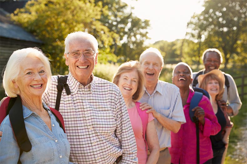 A group of senior friends smiling and laughing while out for a hike in the countryside