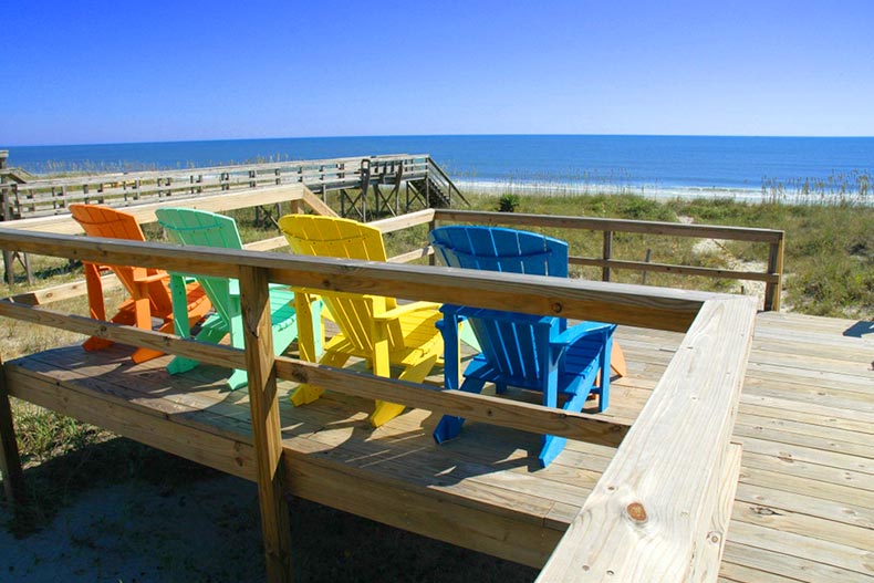 Colorful Adirondack chairs on a deck overlooking a beach