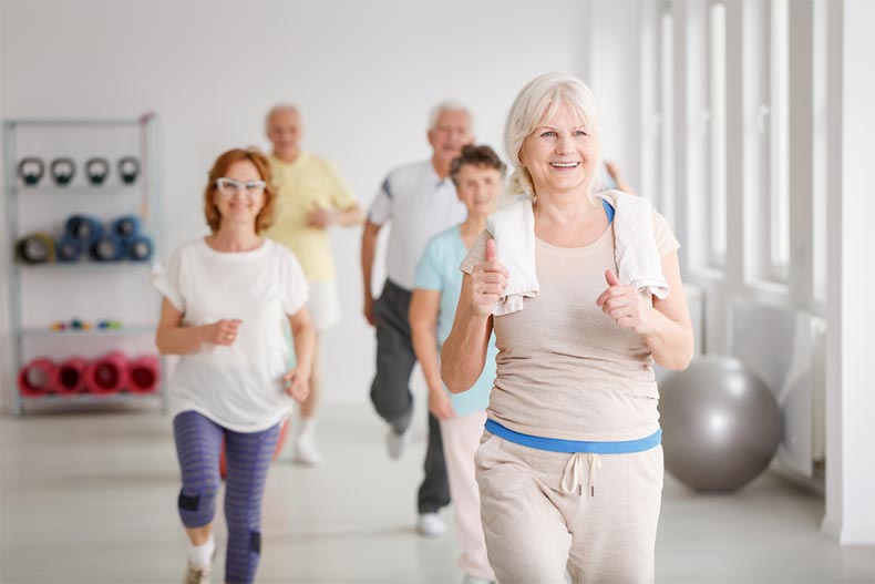 Active seniors smiling while exercising together in a spacious studio