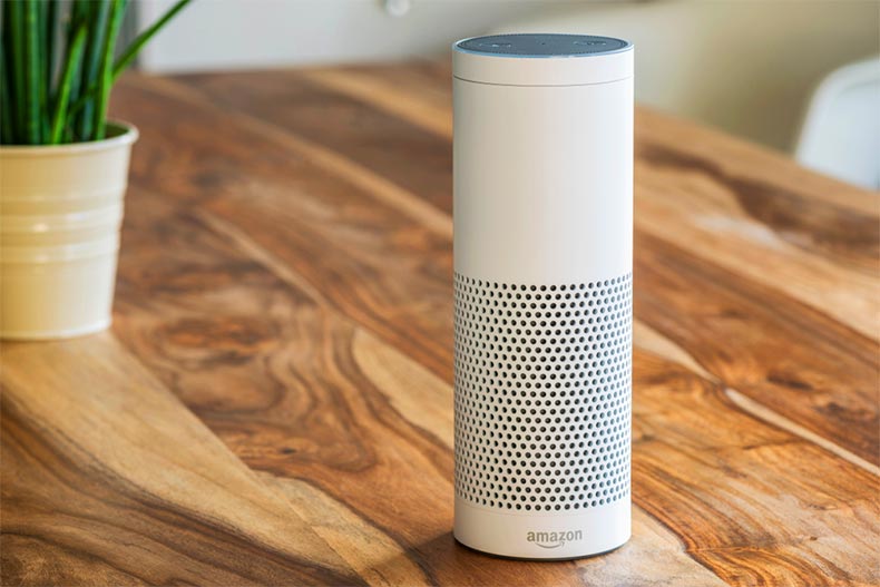 A white Amazon Echo Plus on a wooden table in a living room