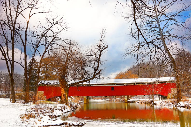 A red covered bridge crossing over a snow-covered riverside in Allentown, Pennsylvania