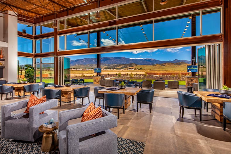 Lounge chairs and tables inside the clubhouse in Altis with mountain views outside of multiple large windows, located in Beaumont, California