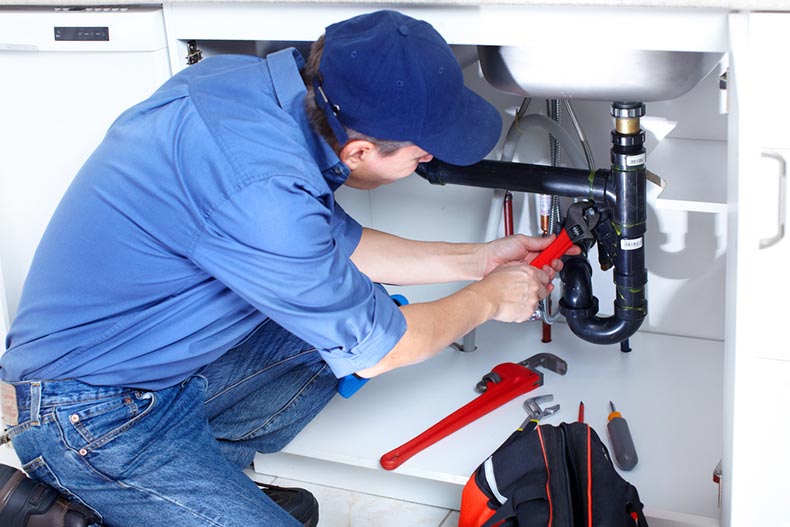 A plumber fixing a sink before a homebuyer closes on the home sale