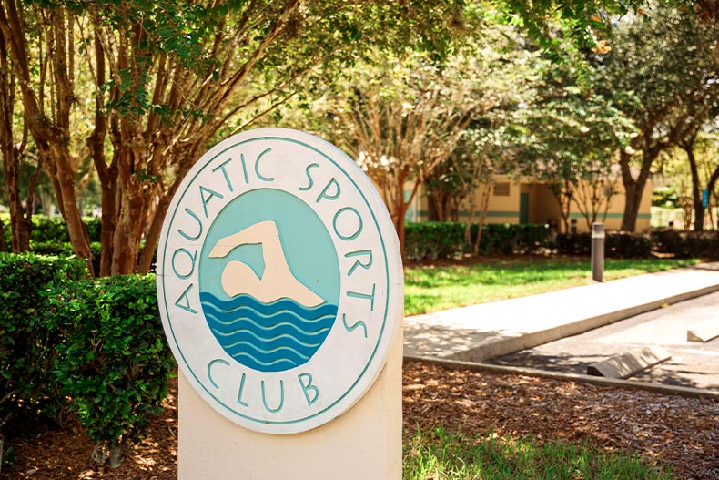 Close up of a sign for the Aquatic Sports Club located in Oak Run of Ocala, Florida, with a white and blue swimming graphic in the center
