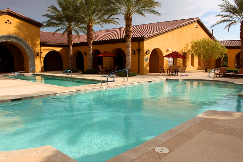 A resort-style pool and lap pool in front of the yellow clubhouse building of Ardiente in North Las Vegas, Nevada