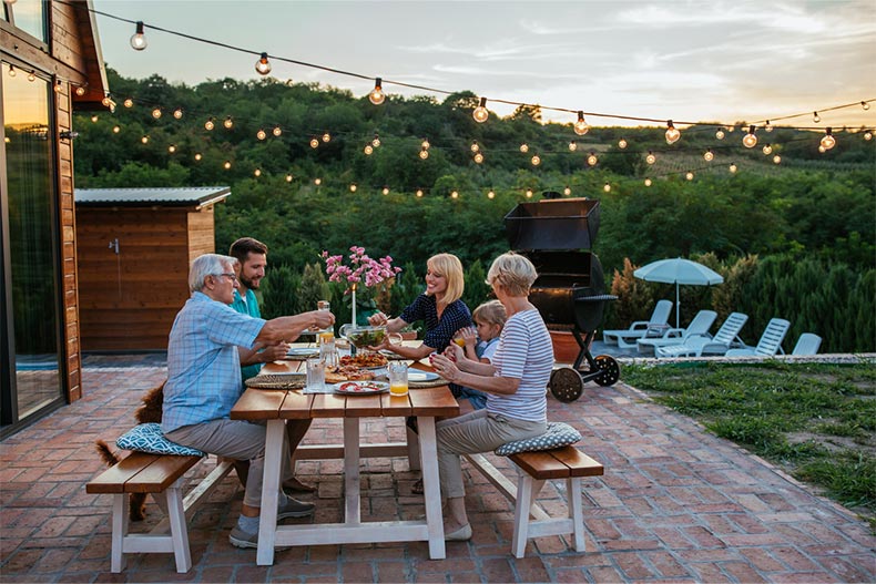 A family enjoys a meal in their backyard in their 55+ community