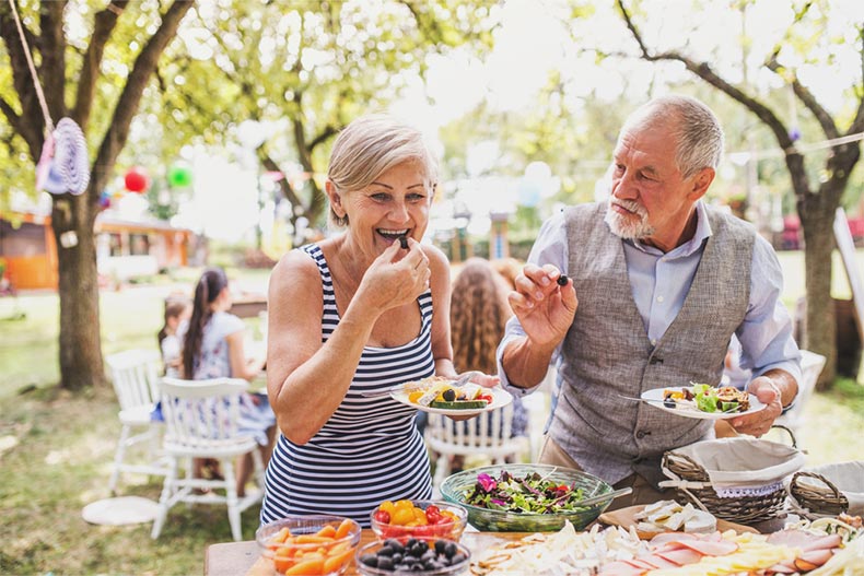 An older couple enjoying food at a garden party in a backyard in a 55+ community