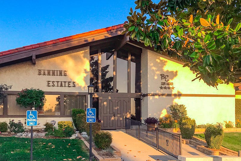 View of the Banning Estates clubhouse with trees and greenery around it at sunset.