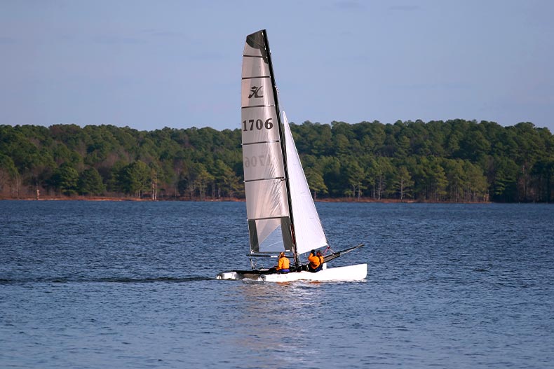 A white sailboat with two passengers on Jordan Lake in North Carolina