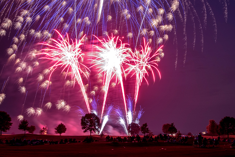 Red and white fireworks lighting up a purple sky over a park in Bolingbrook, Illinois