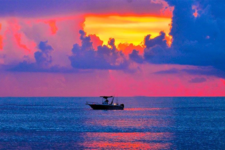 Fishing boat off shore of Boynton Beach with colorful sunrise in background