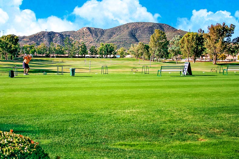 A golfer swinging a golf club on the driving range at Sun Lakes Country Club in Banning, California