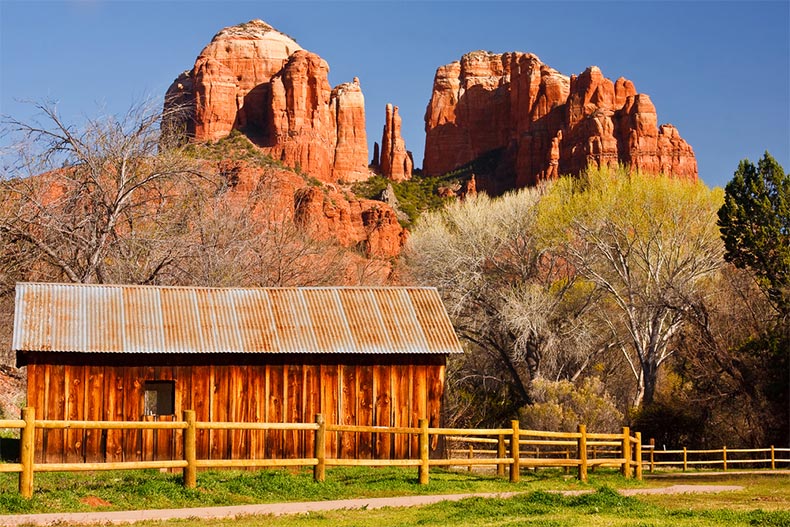 A fence and a barn standing beside Cathedral Rock in Sedona, Arizona