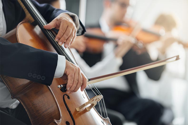 Closeup on the hands of a cellist in a string section of an orchestra