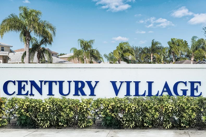 Palm trees and greenery surrounding the community sign for Century Village at West Palm Beach in West Palm Beach, Florida