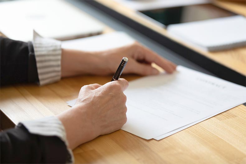 Closeup on a hand writing with a pen on official documents