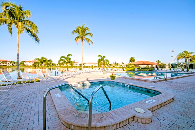 A whirlpool spa, pool, and patio overlooking a lake in Cinnamon Cove of Fort Myers, Florida