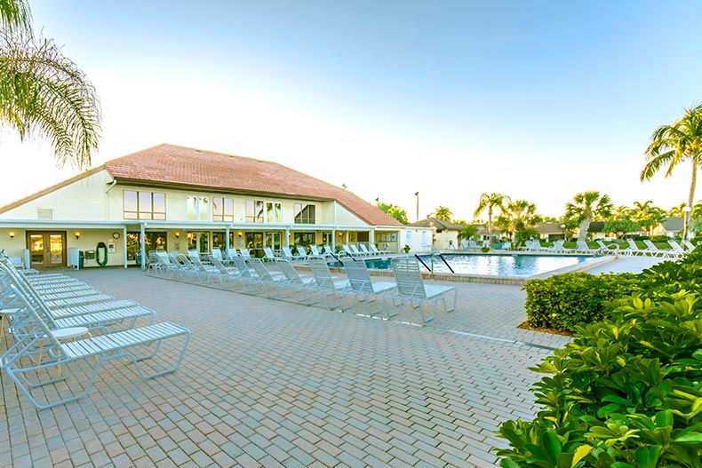 Lounge chairs on the patio surrounding the outdoor pool at Cinnamon Cove in Fort Myers, Florida