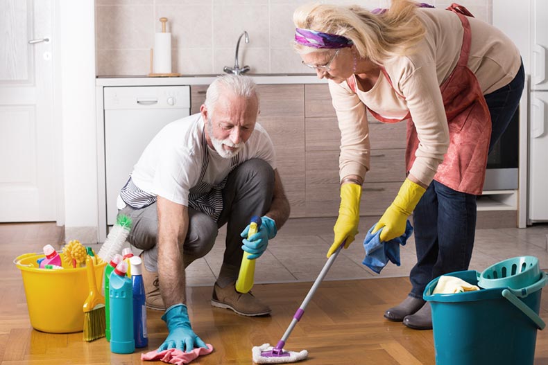 A senior couple working together to clean the kitchen floor