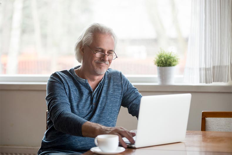 An older man smiling as he learns to code as a retirement hobby