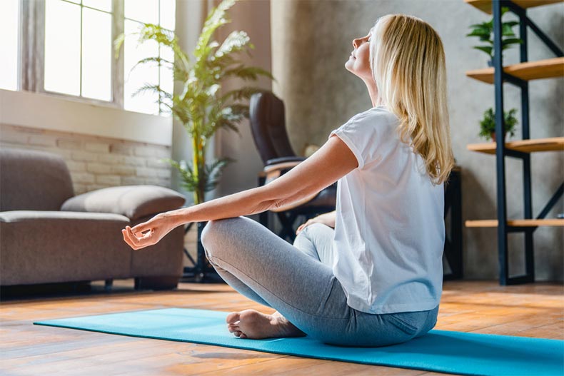 An older woman meditating in lotus position at home