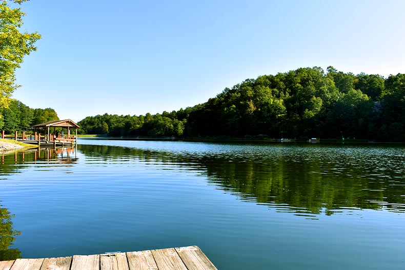 View of a large lake from a wooden dock in Connestee Falls, Brevard, North Carolina. On the opposite side are some trees and another dock.
