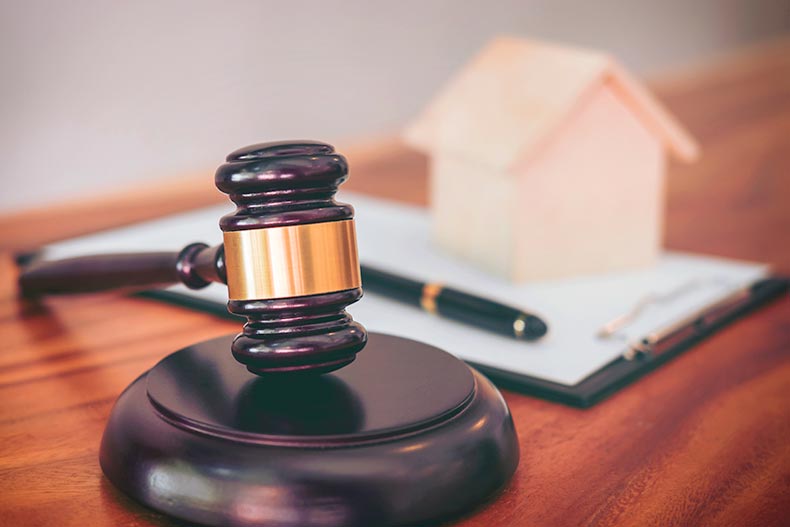 A gavel resting with a toy house and contract in the background
