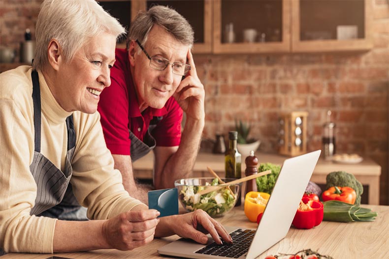 An older couple looking at a recipe online with ingredients laid out on a country