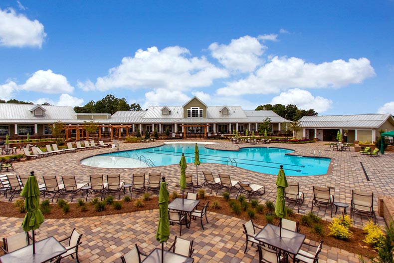 View of the pool and patio area of Cresswind Charlotte with the community clubhouse located in Charlotte, North Carolina