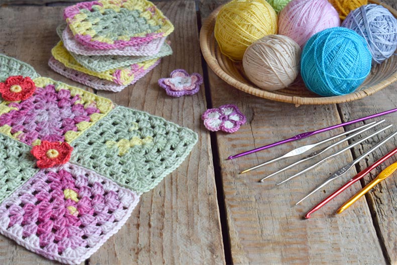 Colorful yarn and hooks for knitting and crocheting laid out on a wooden table