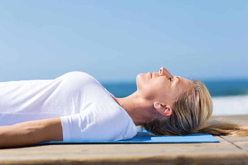 An active adult woman relaxing on a yoga mat
