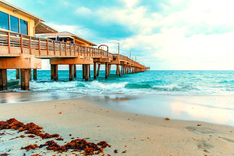 A wooden pier on a beach leading to the ocean in Dania Beach, Florida