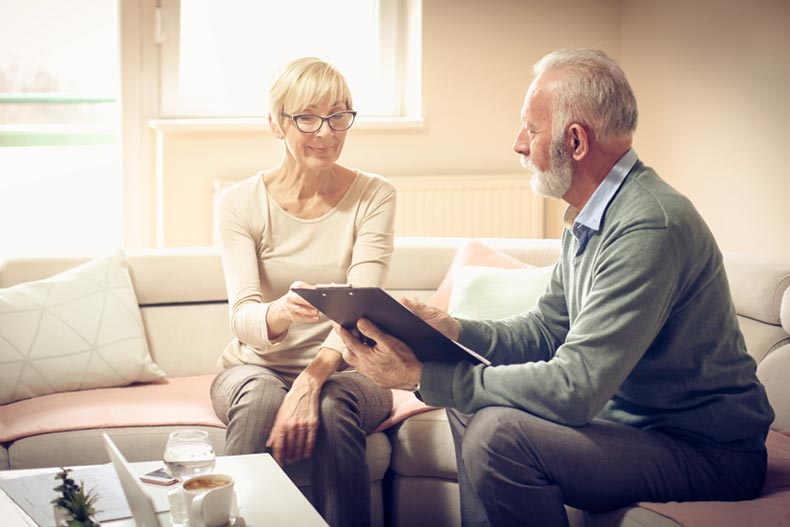 A senior couple sitting on a couch while looking over a deed