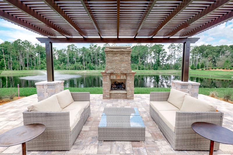 The outdoor patio features a fireplace and overlooks a scenic pond.