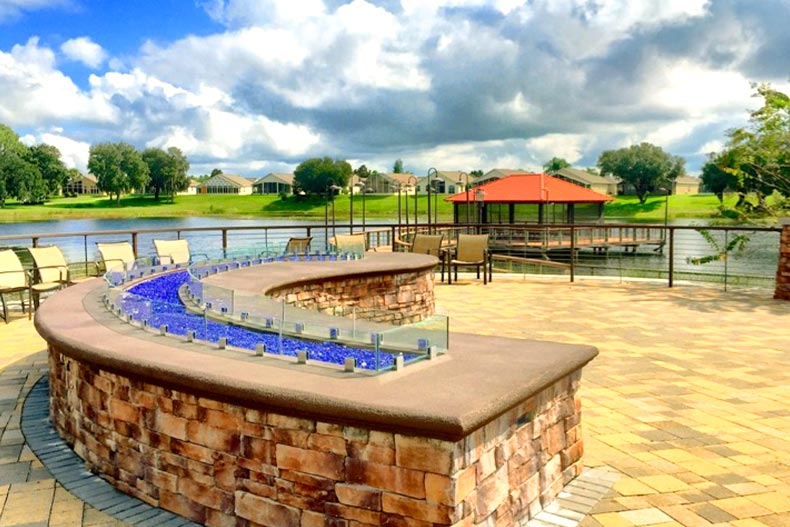 View of a fire pit curving towards a lake pier in Del Webb Orlando, located in Davenport, Florida