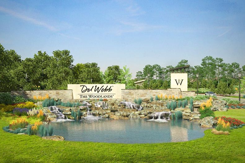Greenery and a water feature surrounding the community sign for Del Webb The Woodlands in The Woodlands, Texas