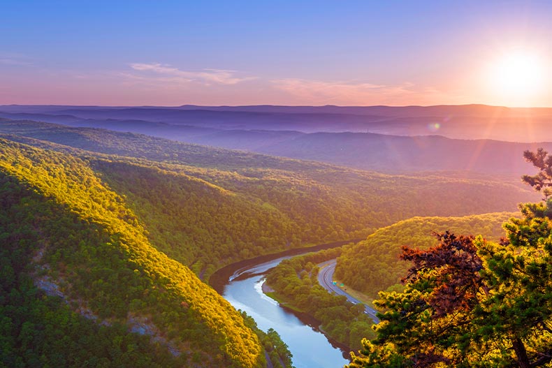 Aerial view of the Delaware Water Gap Recreational Area at sunrise with tree covered mountains and a river running through the middle