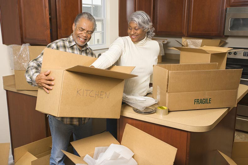 A middle-aged couple packing moving boxes in the kitchen