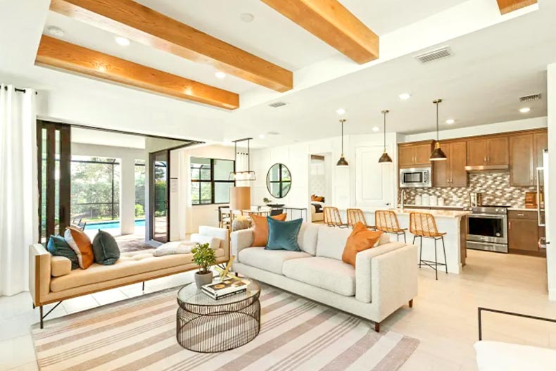 The interior of a model home's open-concept kitchen and living room with a view of a private pool located in Parrish, Florida