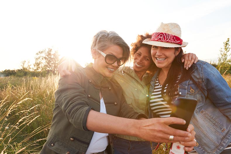 Group of mature female friends walking through a field and posing for a selfie
