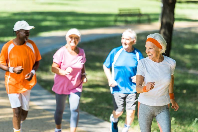 A group of retired friends jogging in a park on a sunny day