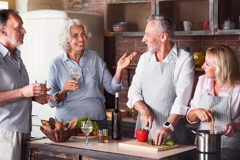 Mature friends laughing and having a conversation in the kitchen
