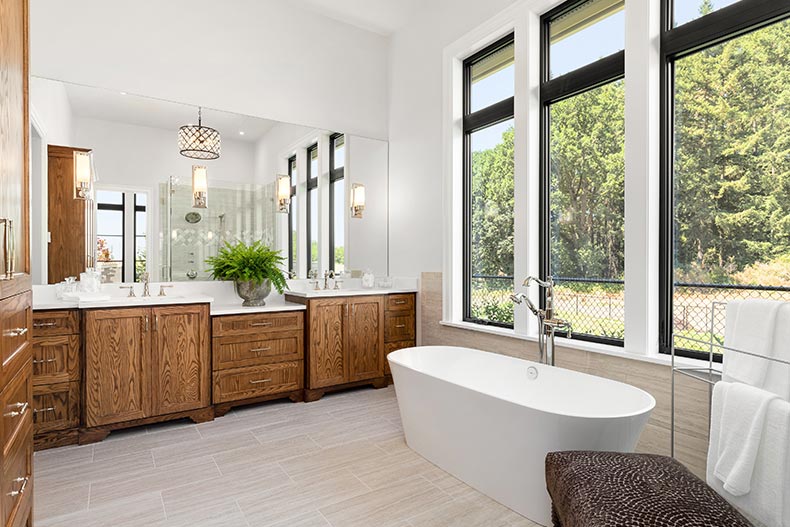 An en suite bathroom with hardwood cabinets and a freestanding bathtub in a new luxury home