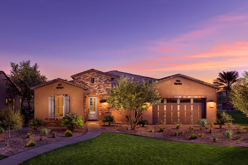 Exterior view of the front of a home in Trilogy at Encanterra at sunset, located in Queen Creek, Arizona