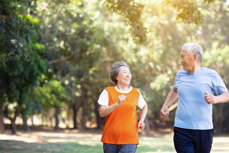 A senior couple jogging together along a community trail on a sunny day