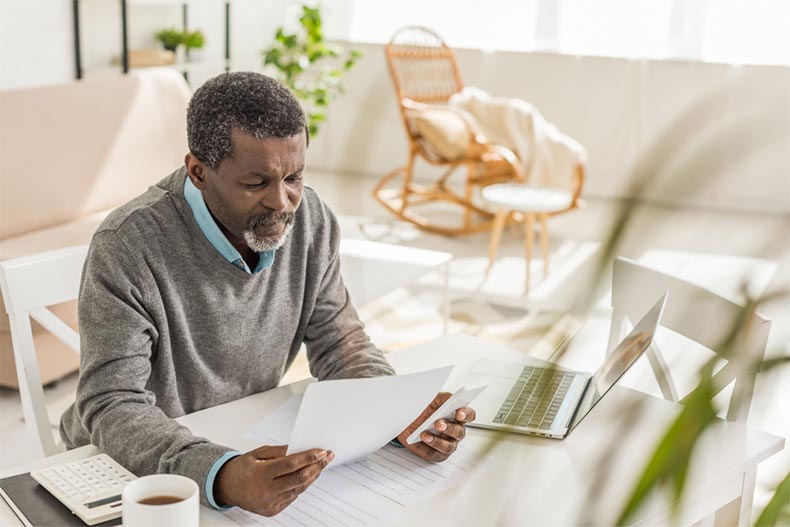 An older man sitting at a desk and estimating the cost of a home in a 55+ community